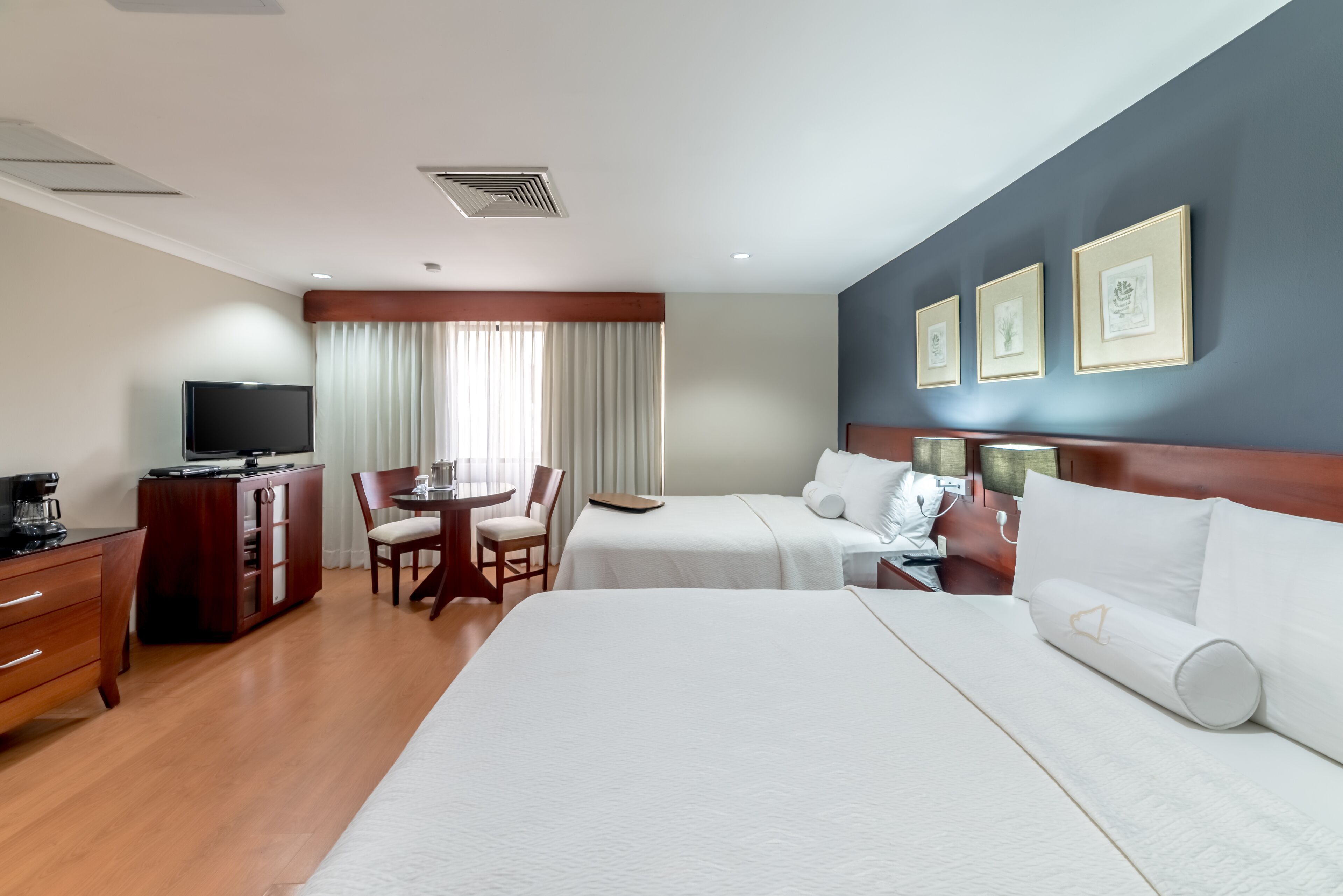 A hotel room with a large bed, a desk with a computer, a chair, and a TV.