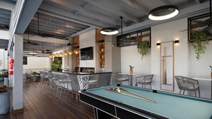 A pool table with chairs, a bar area, and a seating area with plants and a wooden ceiling. - Hodelpa Gran Almirante Hotel & Casino (Santiago de los Caballeros)
