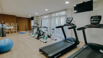 A gym with treadmills, stationary bikes, and a blue exercise ball.
