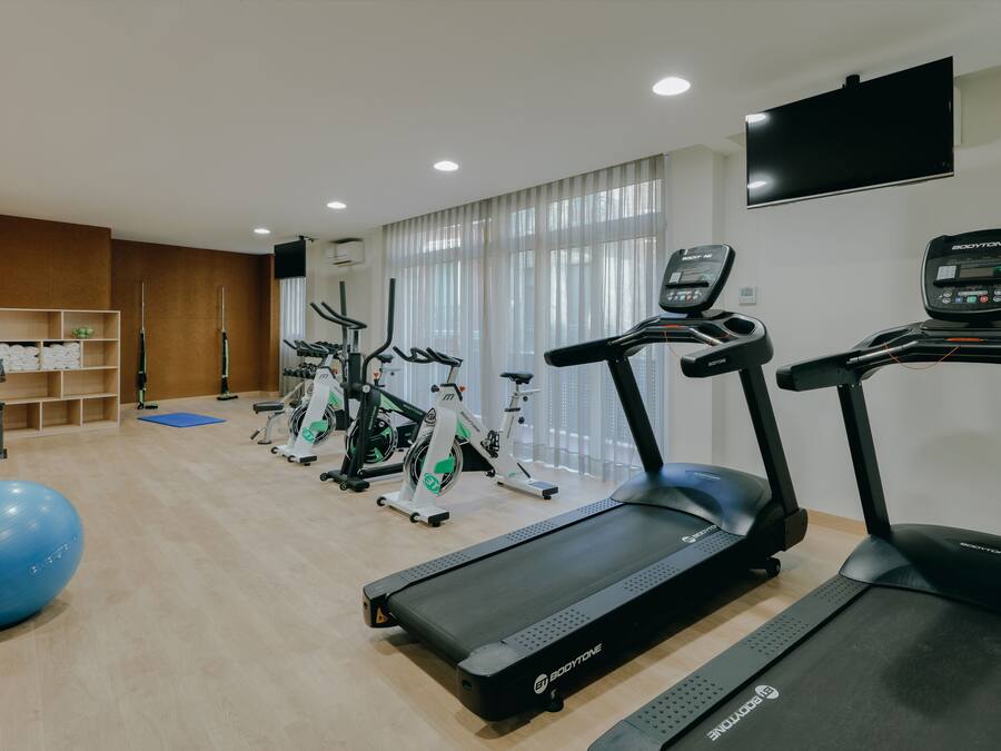 A gym with treadmills, stationary bikes, and a blue exercise ball.