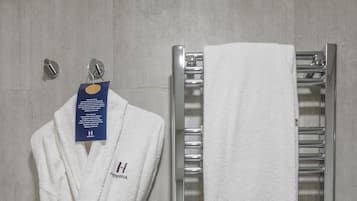 A white robe and towel hanging on a wall-mounted rack in a bathroom.
