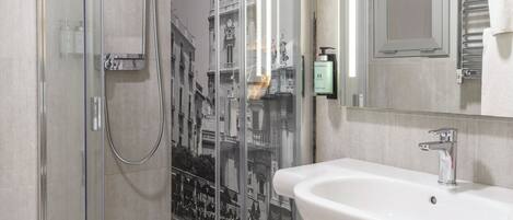 Un baño moderno con cabina de ducha de vidrio, un lavamanos blanco y un espejo.
