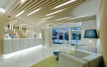A modern reception area with a marble counter, green carpet, and contemporary furniture.
