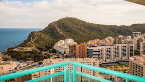 Un paysage urbain côtier avec une colline imposante, des immeubles résidentiels et une vue dégagée sur la mer.