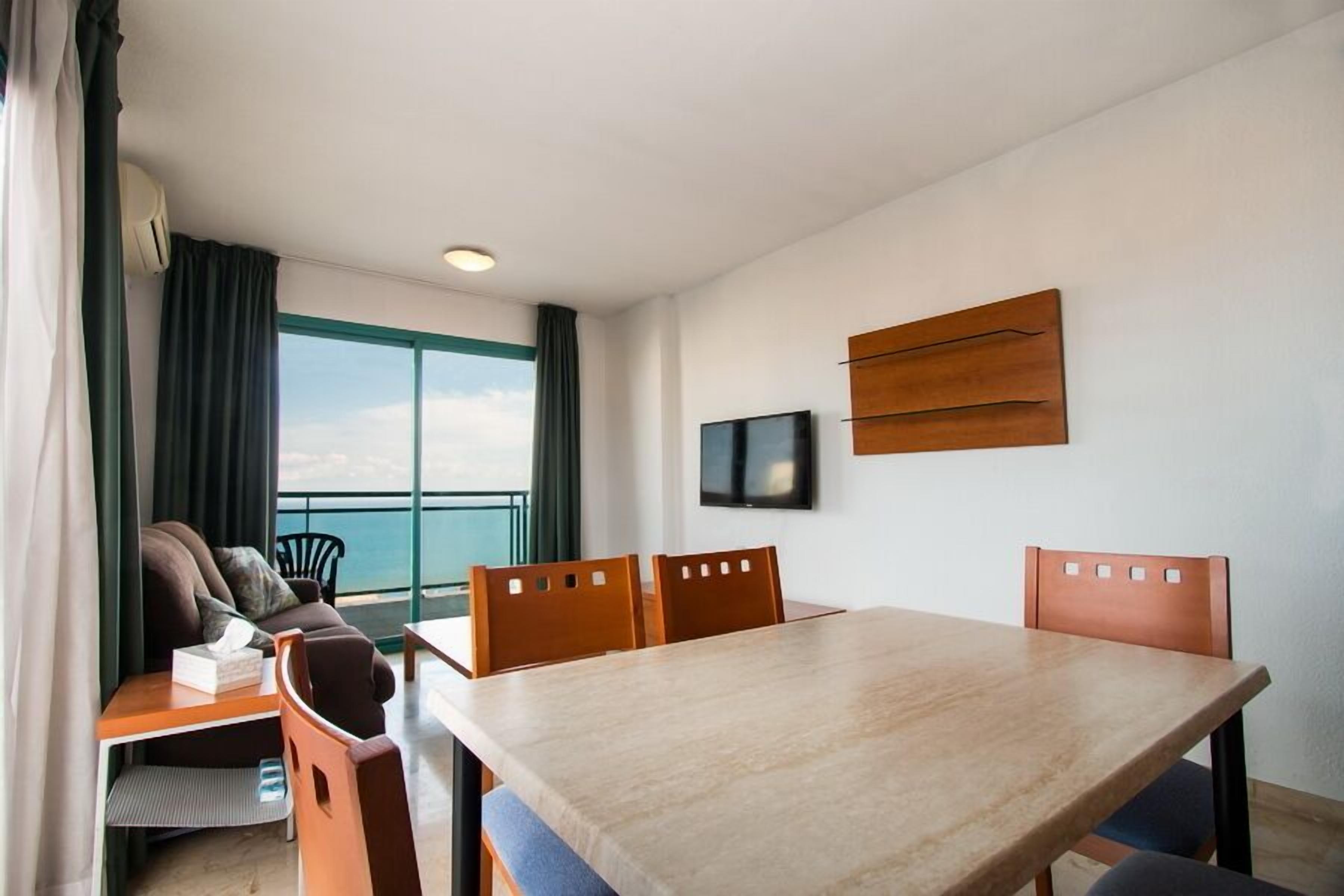 Une chambre d’hôtel moderne dotée d’une grande fenêtre, d’une table à manger et d’un canapé.