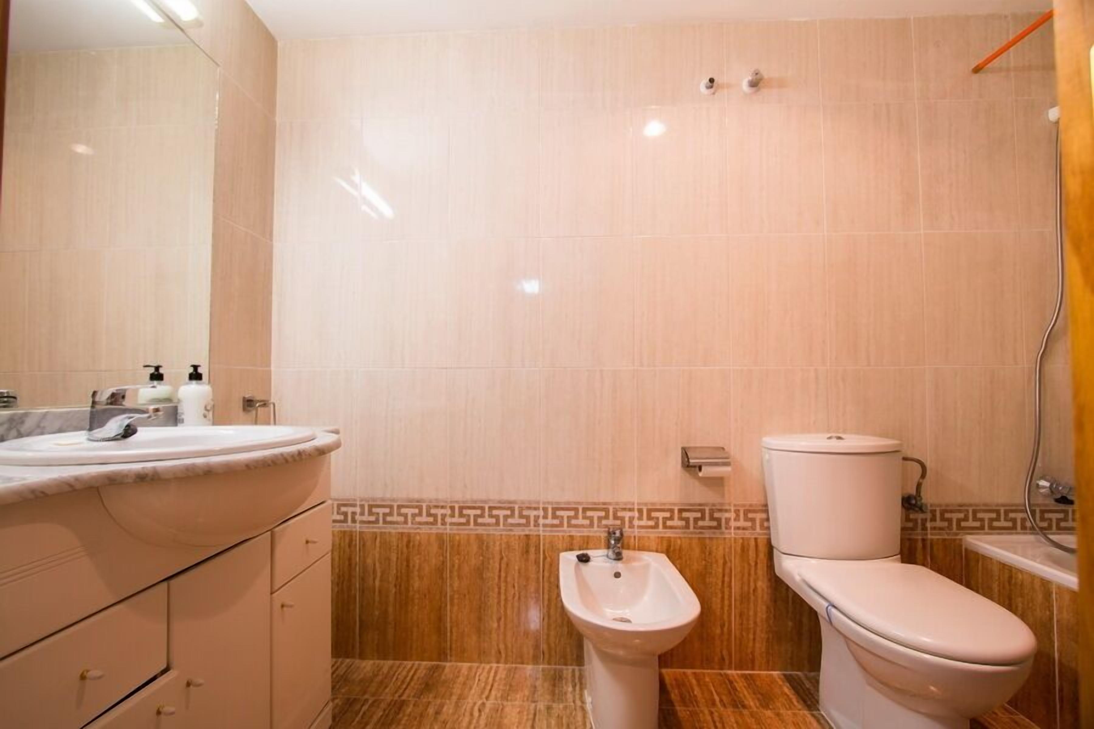 A bathroom with a sink, bidet, toilet, and a mirror.