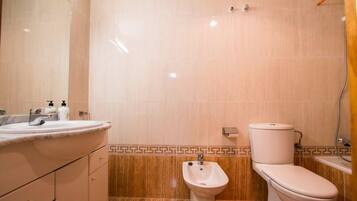 A bathroom with a sink, bidet, toilet, and a mirror.