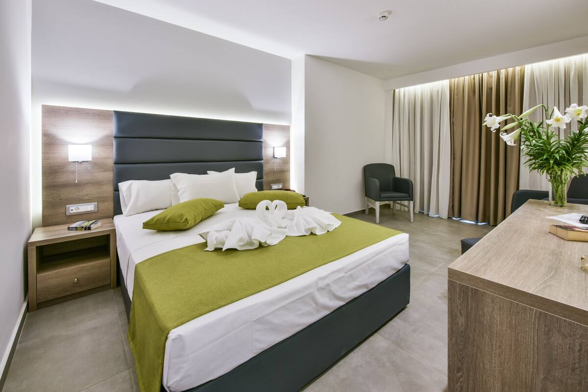 A modern hotel room with a large bed, a desk, and a chair.