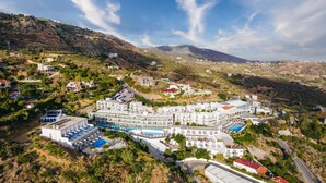 Una località balneare con diversi edifici, una piscina e montagne sullo sfondo.