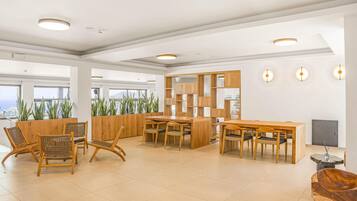 A spacious lobby with a wooden reception desk, seating area with chairs, and a view of the city through large windows.