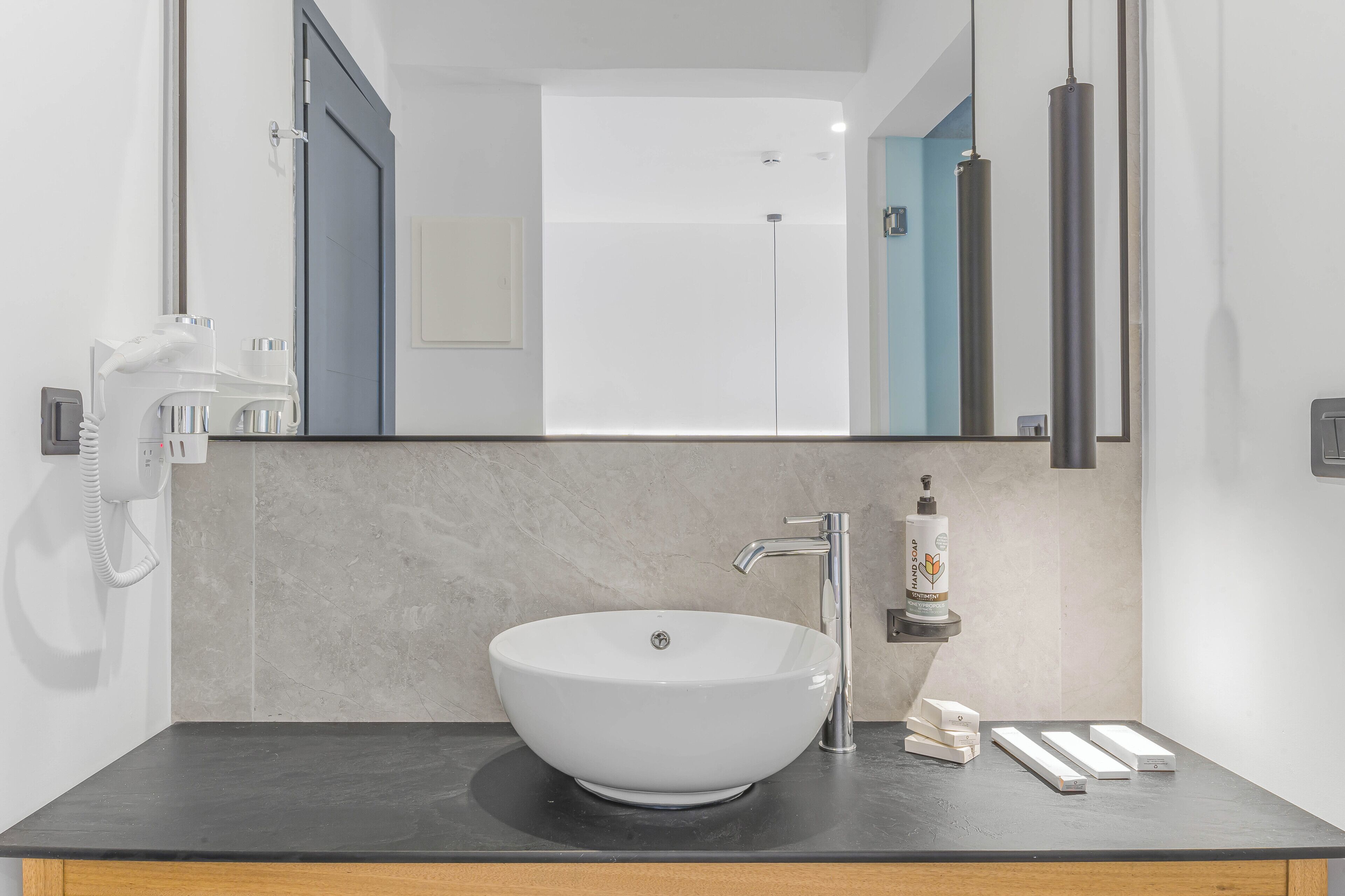 A modern bathroom with a large white vessel sink, a mirror, and a black countertop.