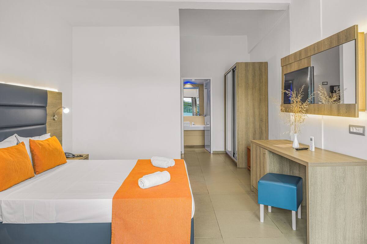 A modern hotel room with a large bed, a desk, and a mirror.