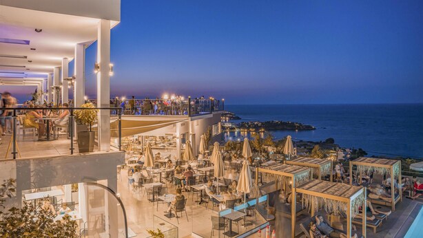 Un bar sul tetto con posti a sedere all'aperto e vista sul mare.