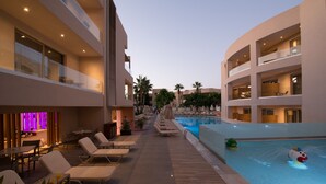 Ett område vid poolen med solstolar, en bar och en pool med en dekorativ vattenfontän.