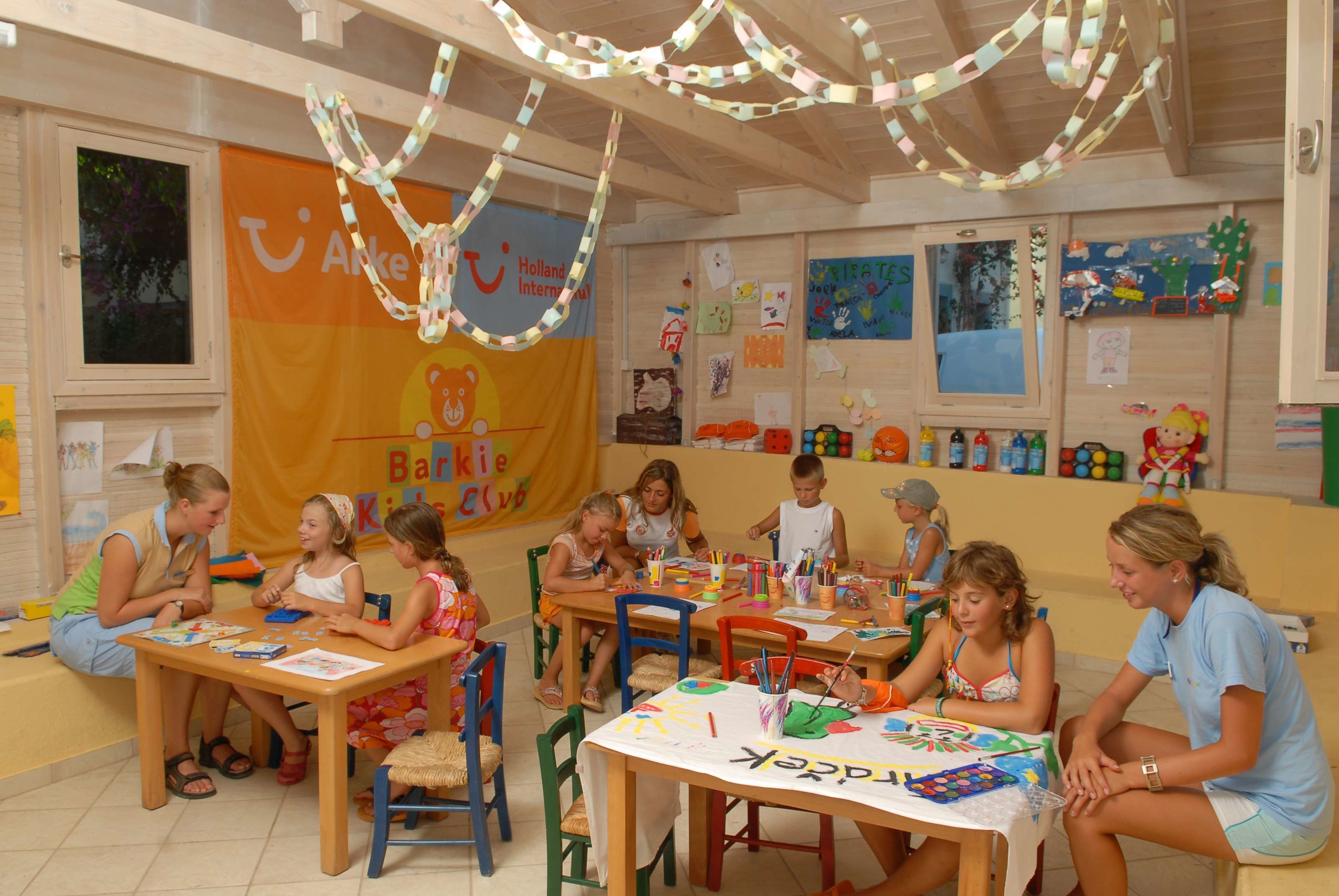 A classroom with children engaged in activities, wooden furniture, and educational posters on the walls.