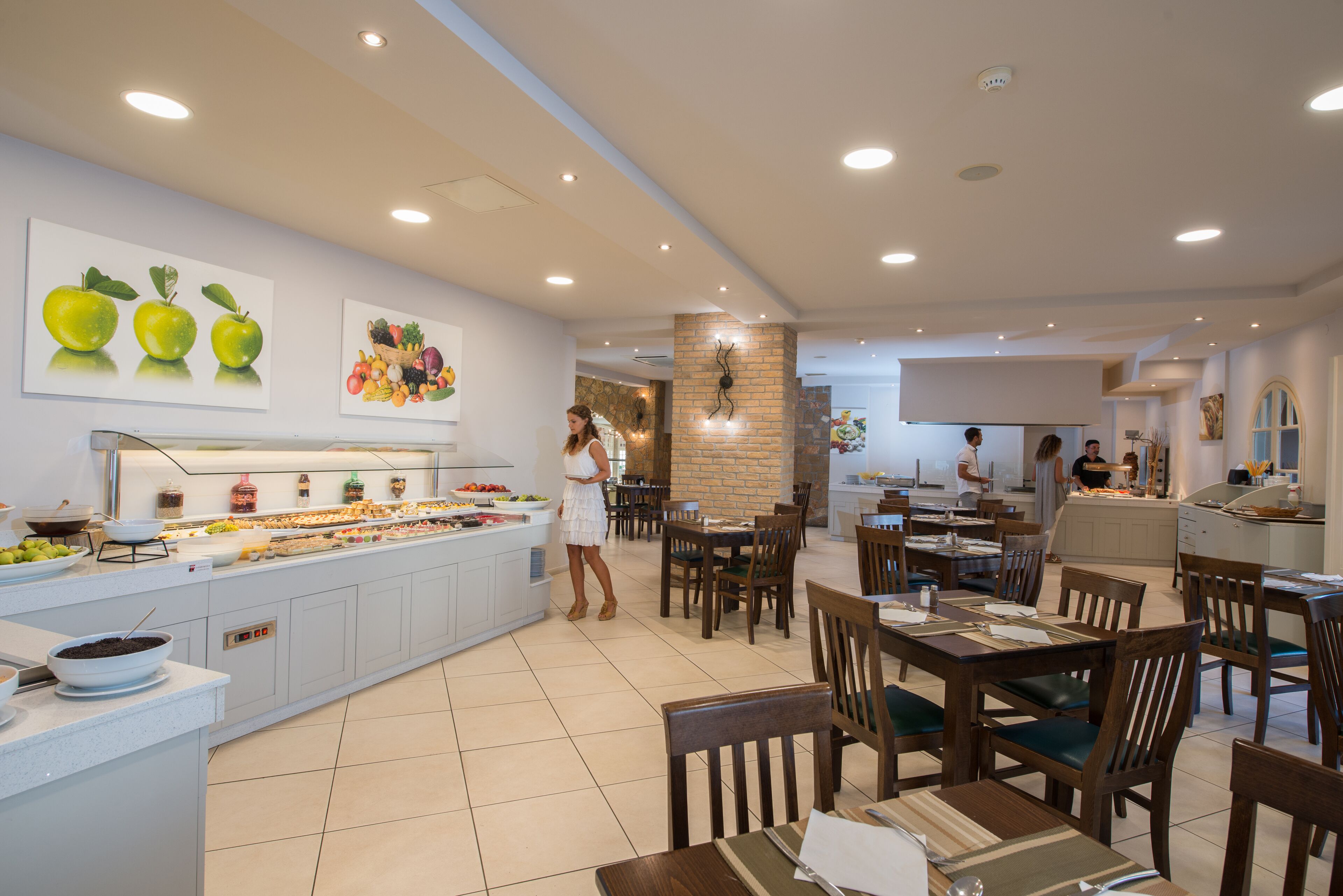 A hotel dining area with a buffet, wooden tables, and chairs.