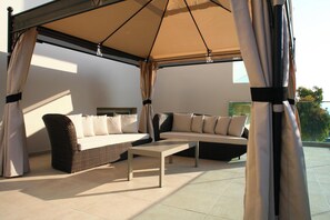 An outdoor seating area with a sofa, a chair, and a table under a canopy. - Golden Beach Hotel (Hersonissos)