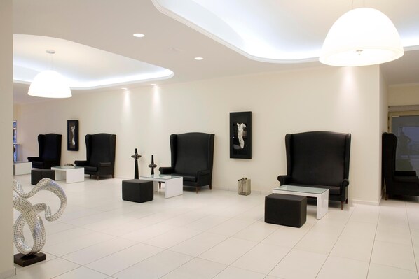 A modern living room with black sofas, a glass coffee table, and a white floor. - Golden Beach Hotel (Hersonissos)