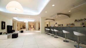 A modern bar area with a long counter, multiple stools, and a television. - Golden Beach Hotel (Hersonissos)