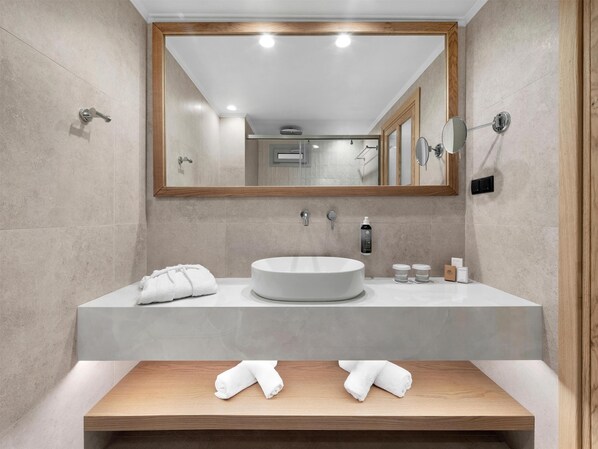 A modern bathroom with a large mirror, a round sink, and two towels on the counter.