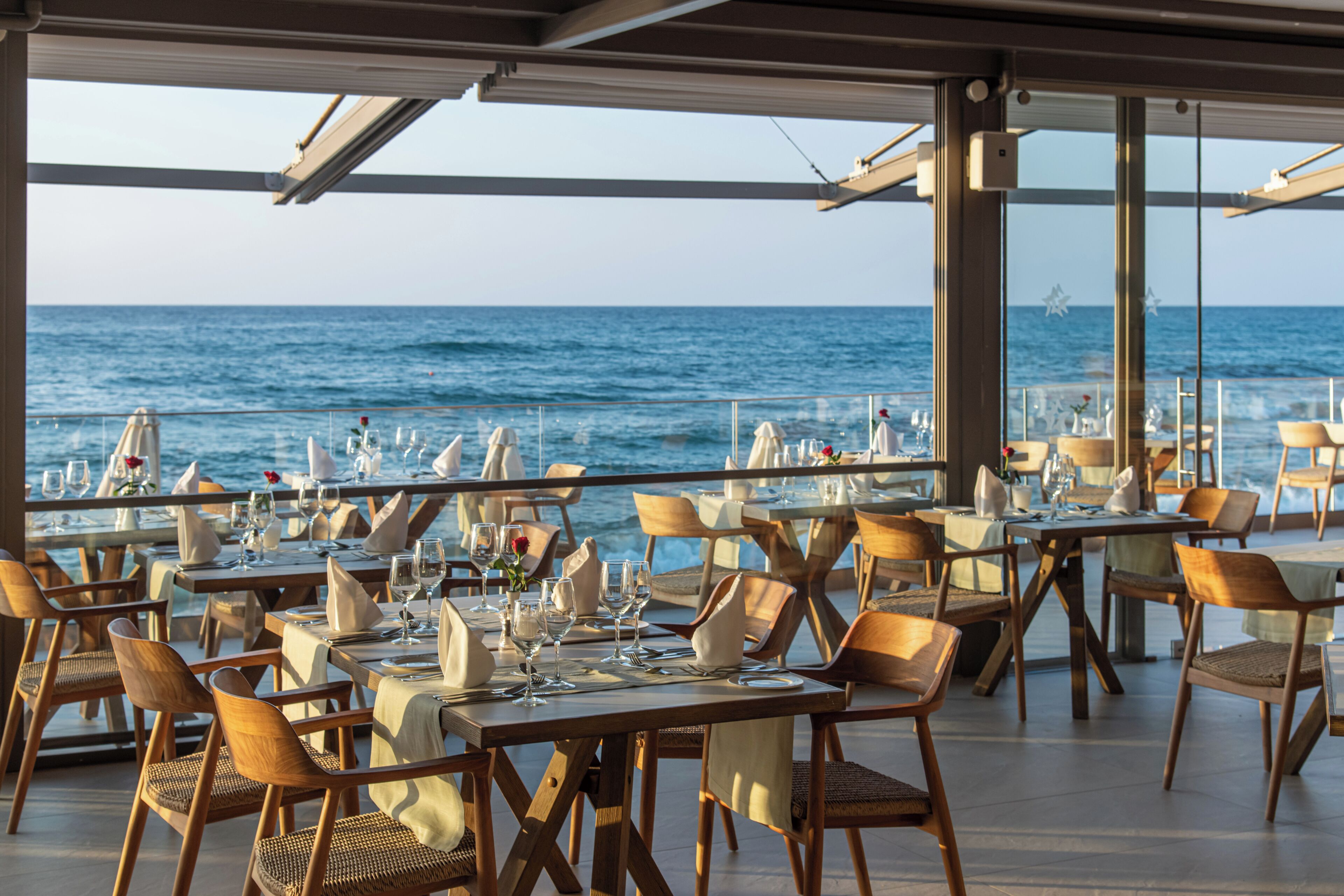 A seaside restaurant with tables set for dining, overlooking the ocean.