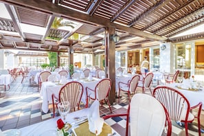 Enjoy a formal dining experience under a shaded pergola with beautifully set tables and comfortable seating.
