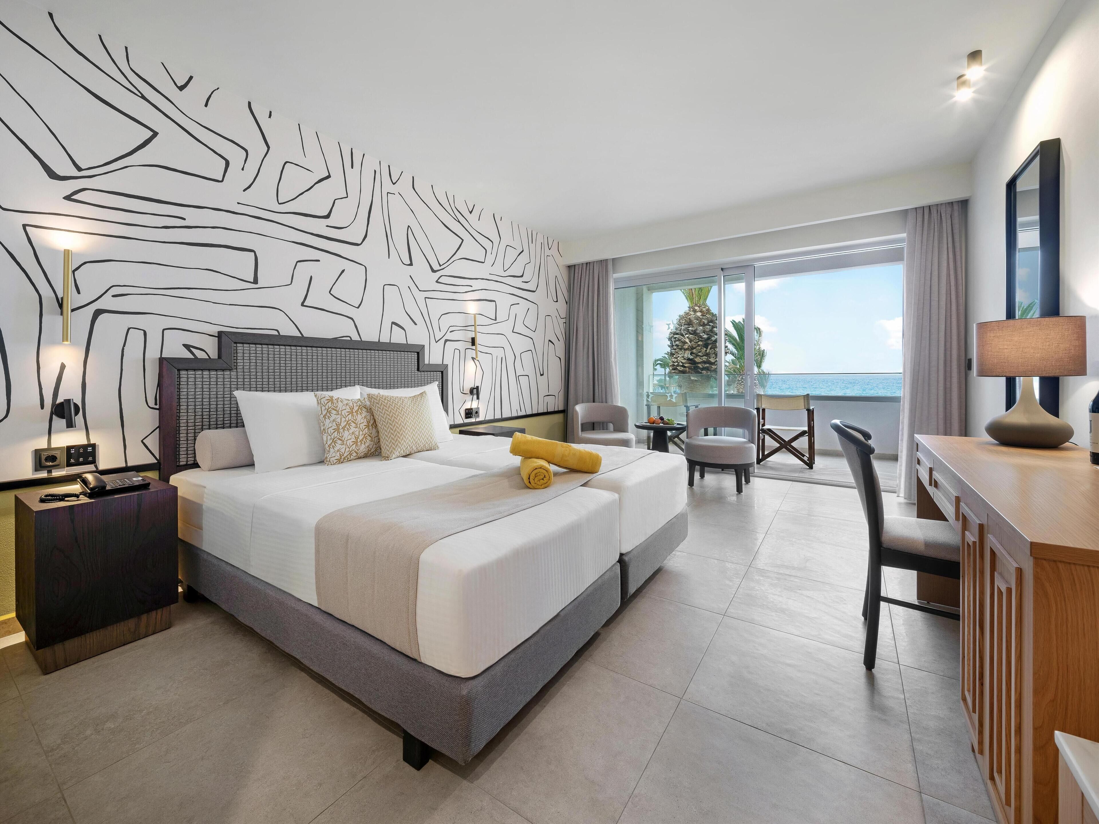 Una habitación de hotel moderna con una cama grande, un escritorio y vista al océano.