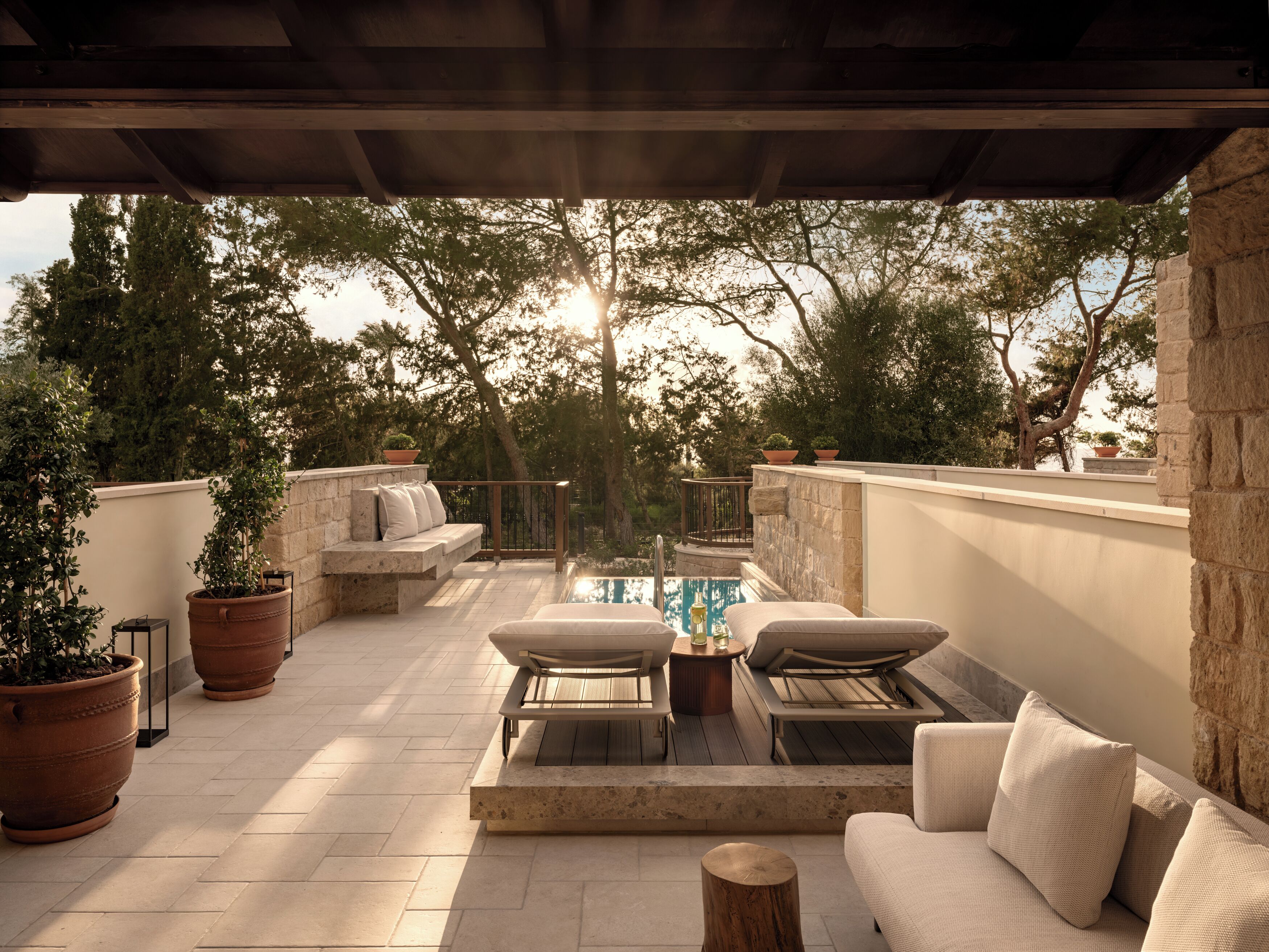 Une terrasse extérieure avec une piscine, des sièges et des plantes en pot.