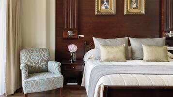 A bedroom with a large bed, a nightstand, a chair, and two framed pictures on the wall.
