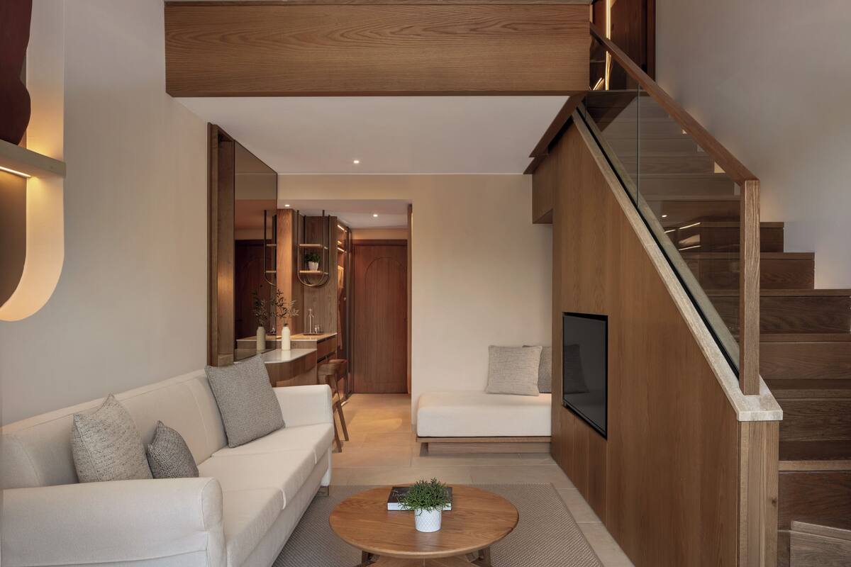 A modern interior with a loft bedroom, a sofa, a coffee table, and a staircase.
