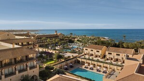 A resort with multiple buildings, a central pool, and a view of the ocean.