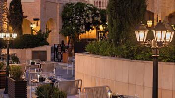 An outdoor patio with tables and chairs, surrounded by planters and a stone wall.