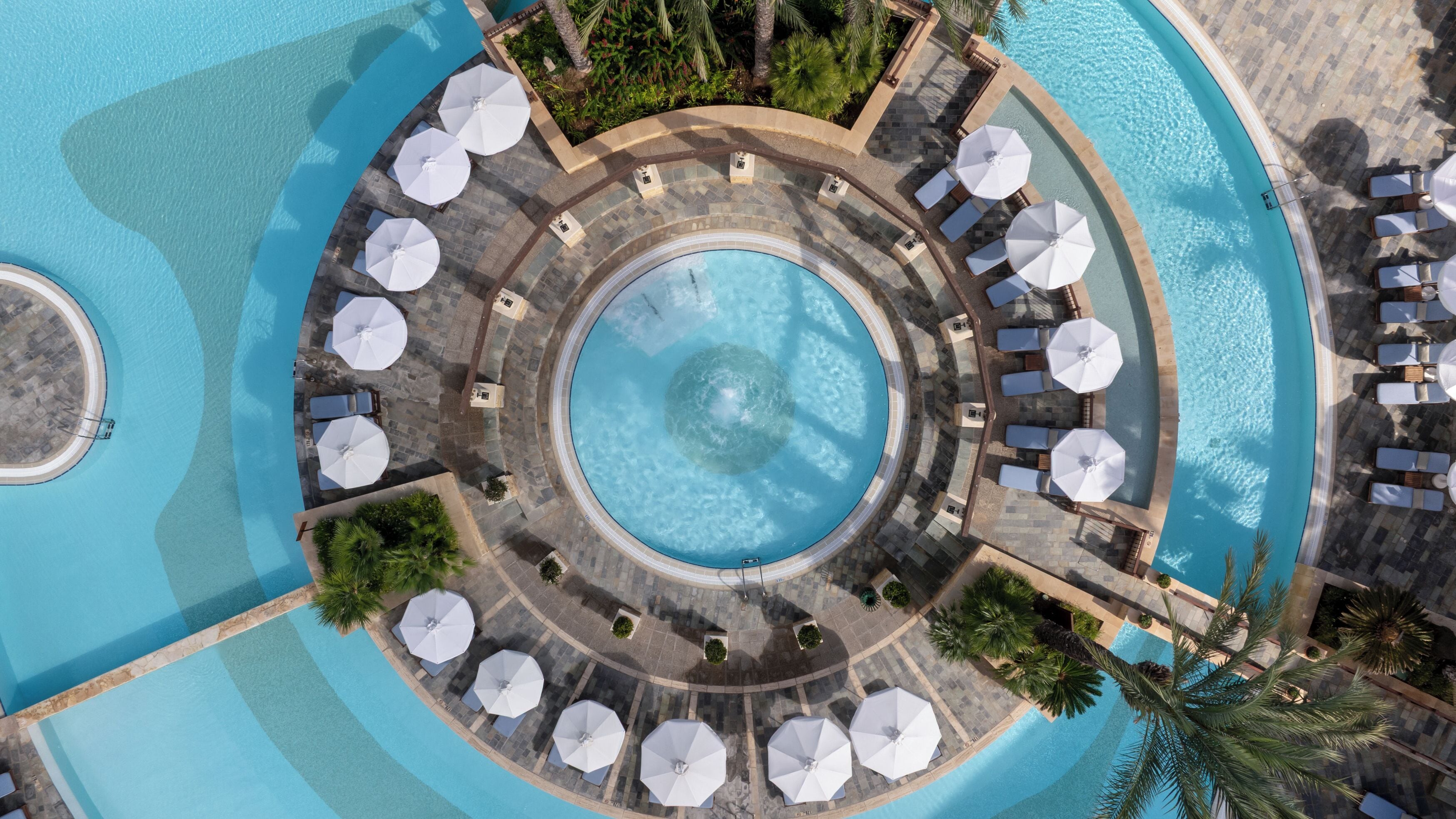 A circular pool with surrounding lounge areas and umbrellas.