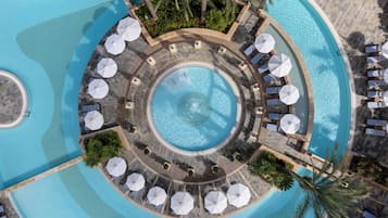 Una piscina circular con zonas de descanso y sombrillas alrededor.