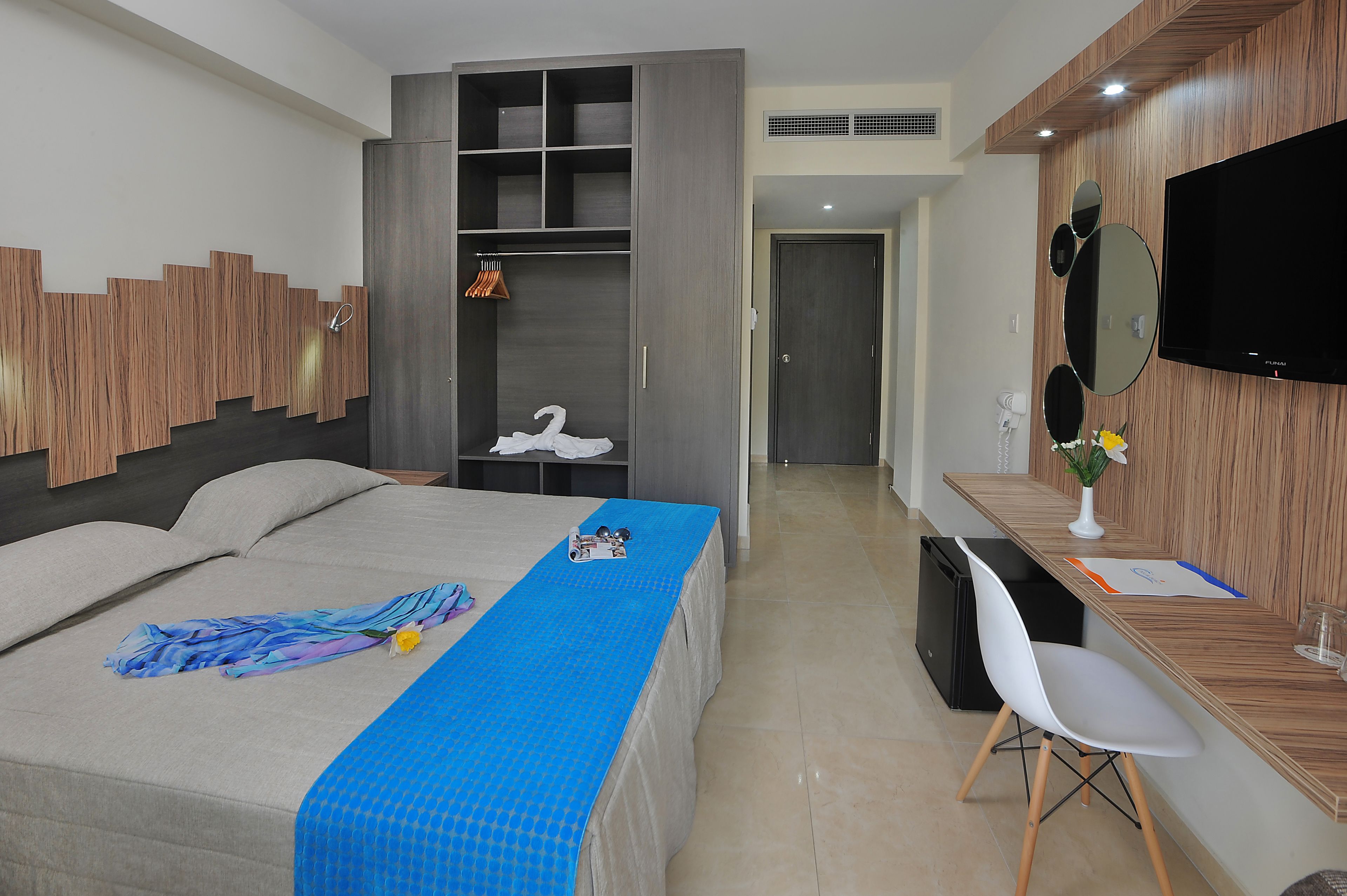 A hotel room with a bed, a desk, a wardrobe, and a TV.