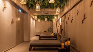 Een spa-ruimte met een massagetafel, kaarsen en decoratieve wandversiering.