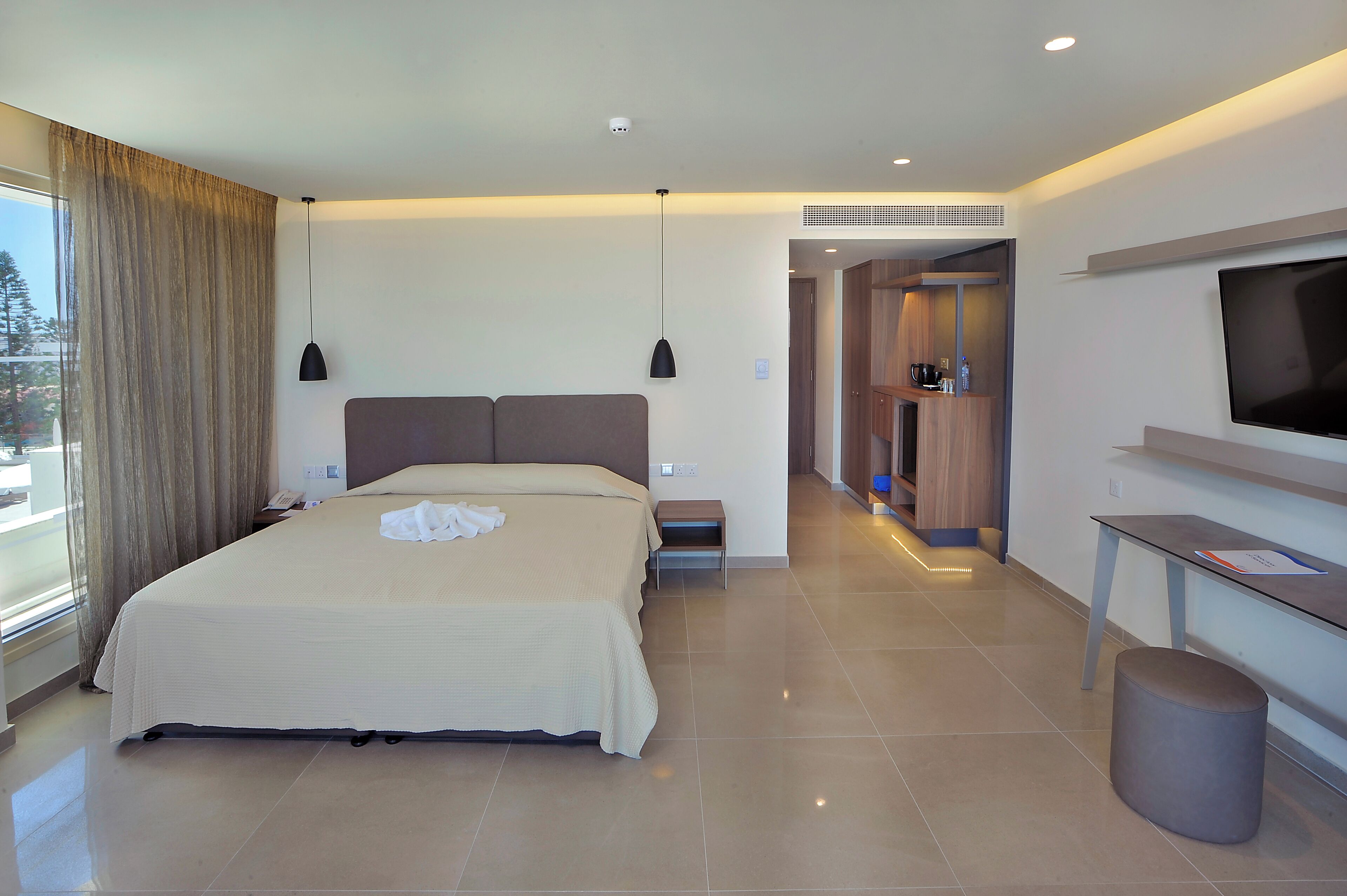 Una habitación de hotel moderna con una cama grande, un televisor y una mesita.