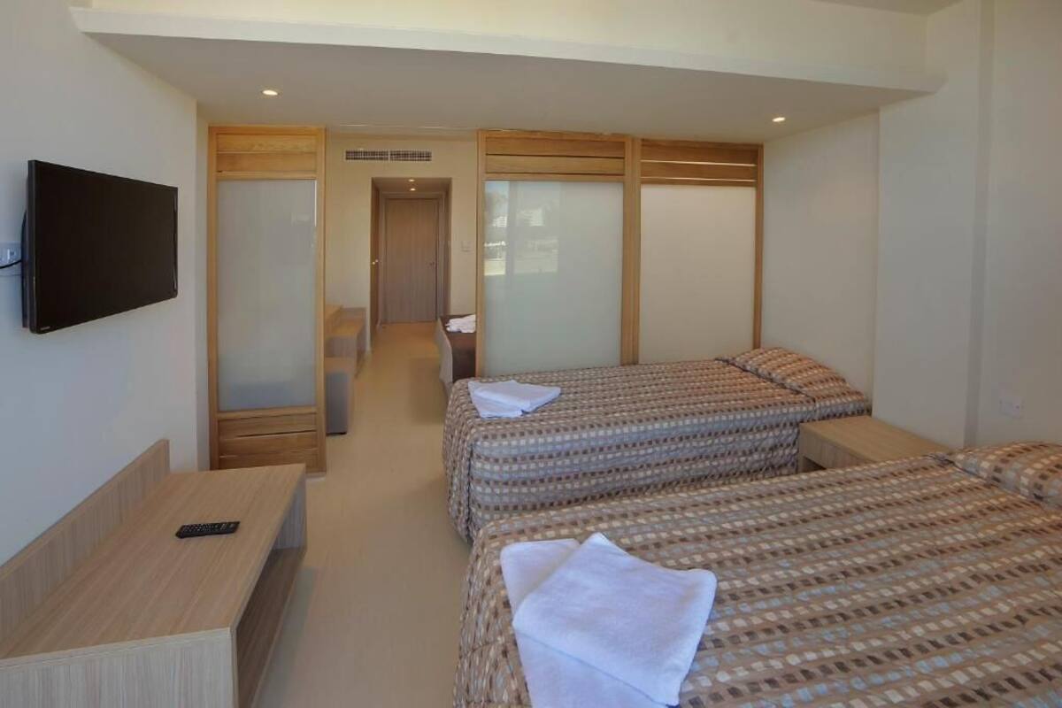 Une chambre d’hôtel avec deux lits, une télévision, un bureau et un placard à portes coulissantes.