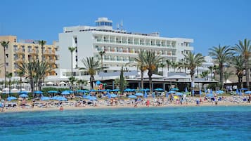 Un hotel con diversi piani, una zona piscina e ombrelloni sulla spiaggia.