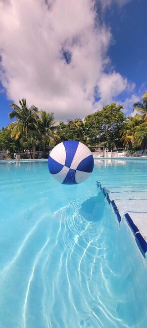A clear blue pool with a blue and white beach ball floating on the water.