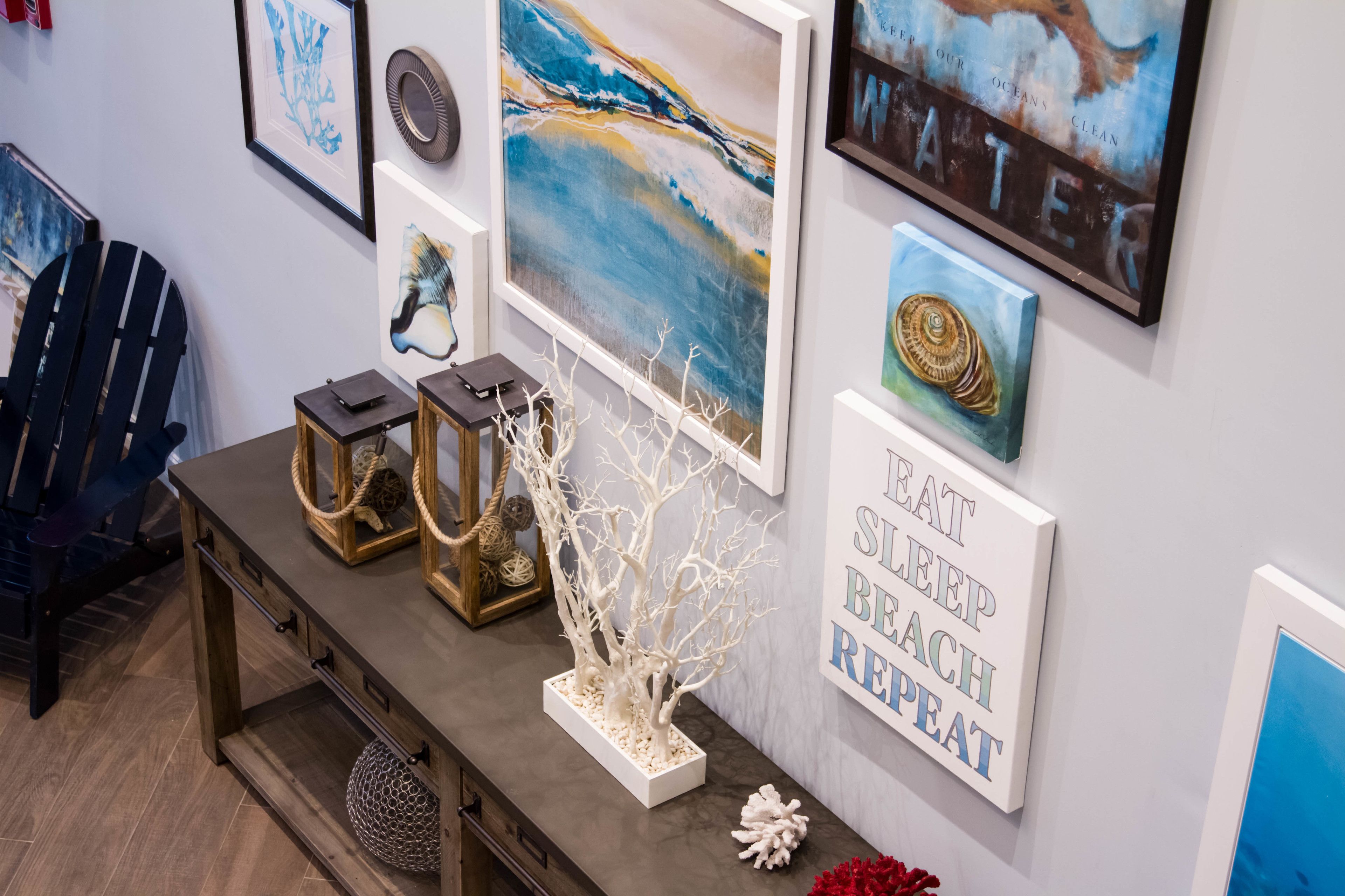 Un mur orné de divers tableaux encadrés, un arbre décoratif et une pancarte affichant un message motivant.