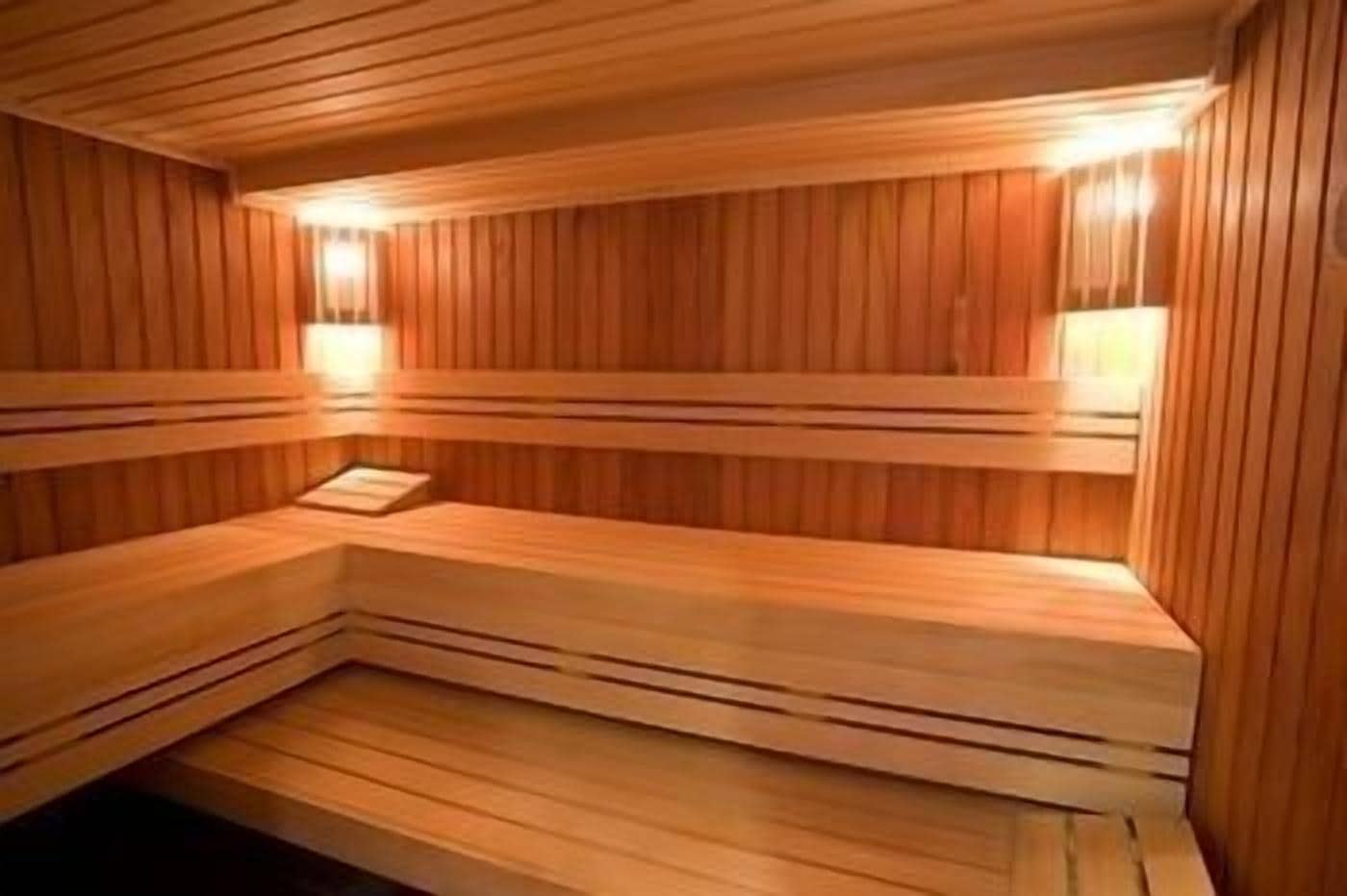 Una sauna con bancos de madera e iluminación en la pared.