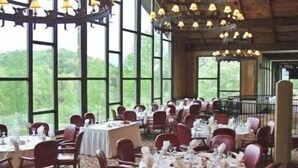 Comedor con mesas redondas dispuestas para el servicio, ventanas amplias y vista a zonas verdes exteriores.