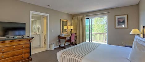 A hotel room with a large bed, a desk with a chair, a television, and a balcony with a view.