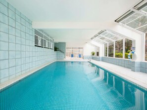 An indoor swimming pool with tiled walls, a glass enclosure, and a lifebuoy. - BreakFree Beachpoint (Surfers Paradise)