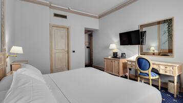 A hotel room with a large bed, a desk with a chair, a television, and a mirror.