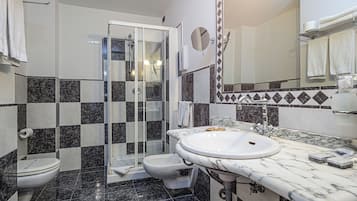 A bathroom with a glass-enclosed shower, a white sink, and a toilet.