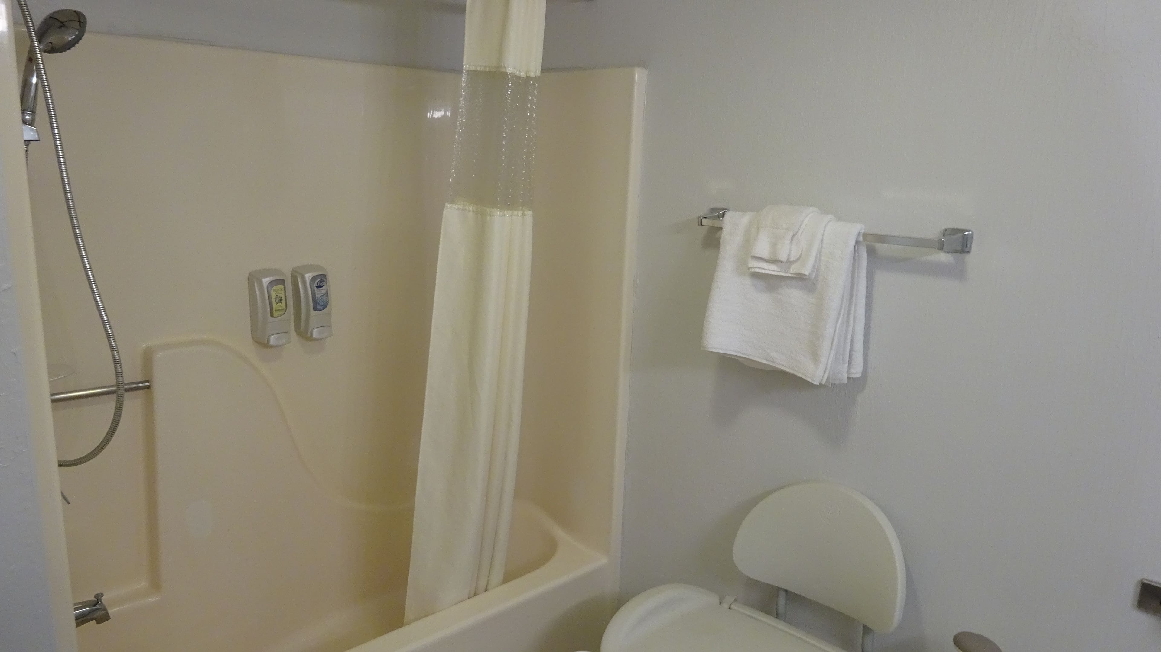 Un baño con ducha, inodoro y toallero.