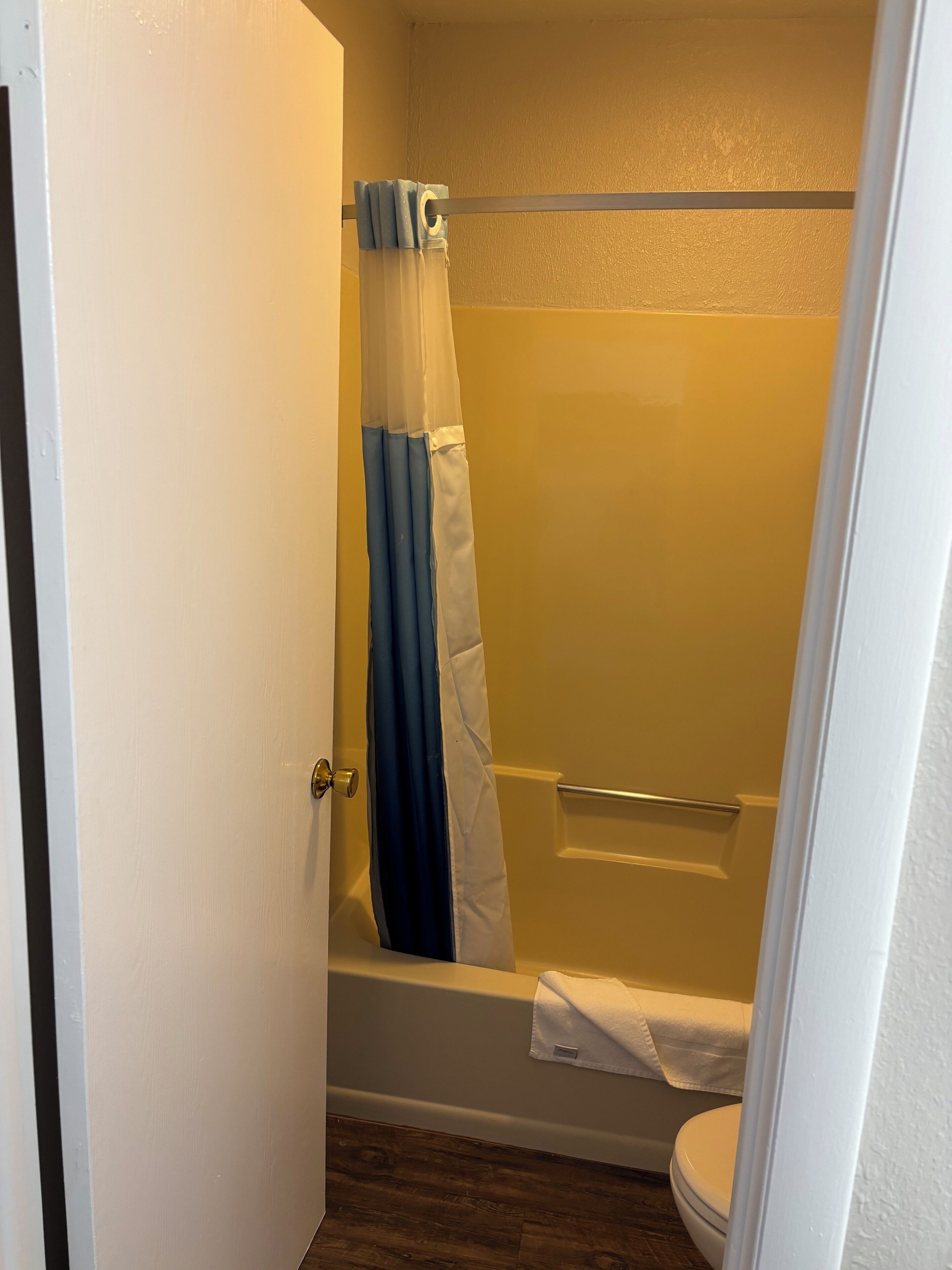 Een badkamer met een bad, douchegordijn en toilet.