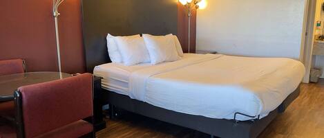 A hotel room with a large bed, a desk with a chair, and two bedside lamps.